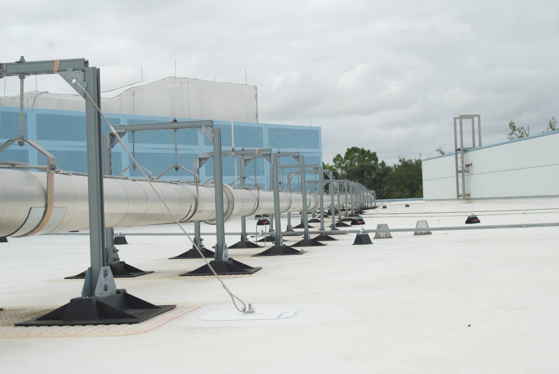 An installer tensioning wire rope on a rooftop anchor